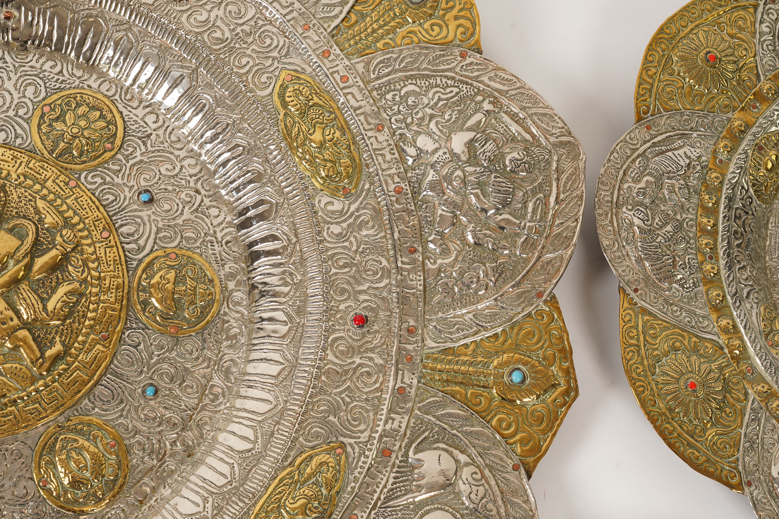 A graduated set of three Nepalese repoussé white metal and brass chargers, first half 20th century